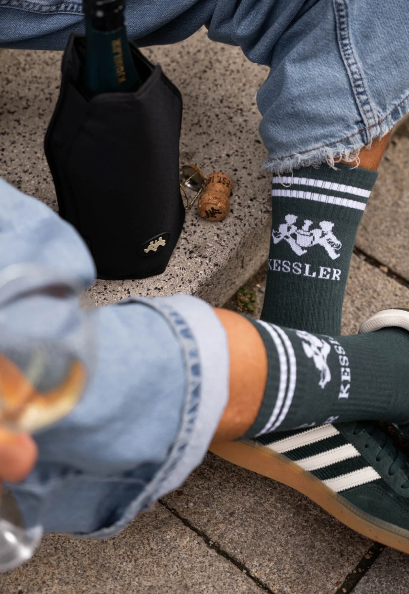 Dunkelgrüne Kessler-Tennissocken mit weißem Schriftzug, dazu ein Glas Sekt